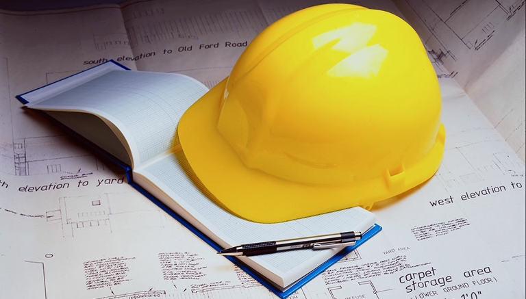 Casco de seguridad amarillo sobre planos de obra